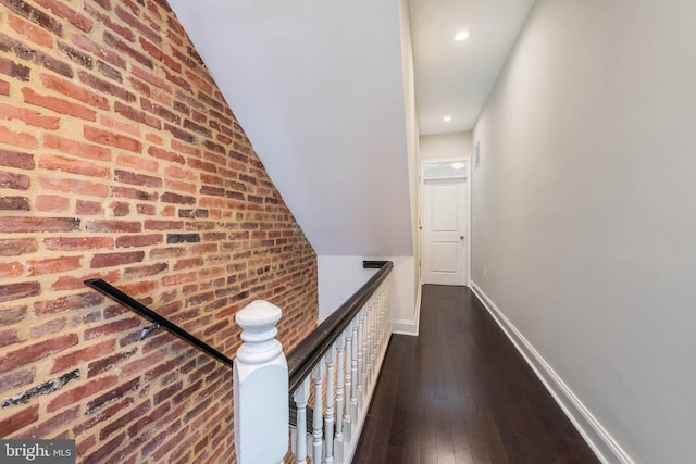 hall featuring brick wall, lofted ceiling, and dark hardwood / wood-style flooring