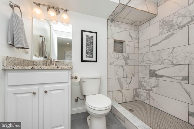 bathroom with vanity, tiled shower, toilet, and tile patterned floors