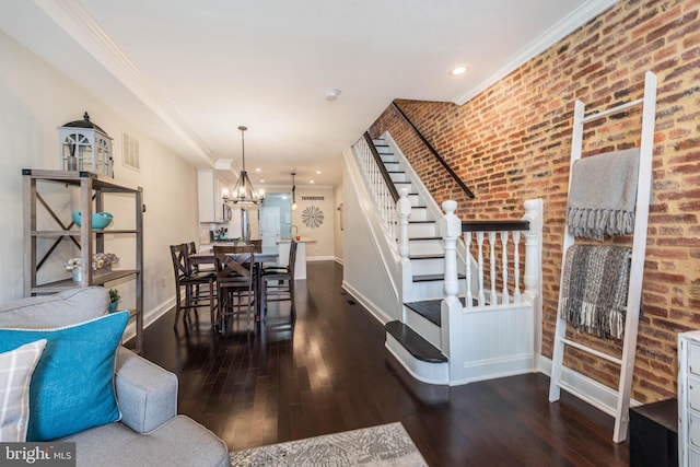 dining area featuring dark wood-type flooring, crown molding, brick wall, and a chandelier