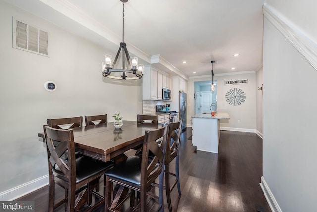 dining room with ornamental molding, dark hardwood / wood-style floors, a chandelier, and sink