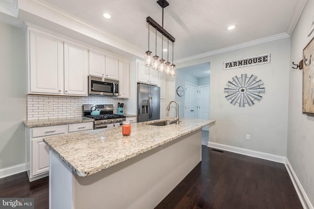 kitchen featuring appliances with stainless steel finishes, pendant lighting, white cabinets, dark wood-type flooring, and a center island with sink