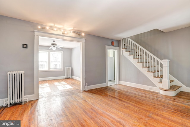 unfurnished living room with wood-type flooring, radiator, and ceiling fan