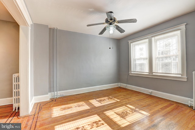 spare room featuring hardwood / wood-style floors, radiator, and ceiling fan