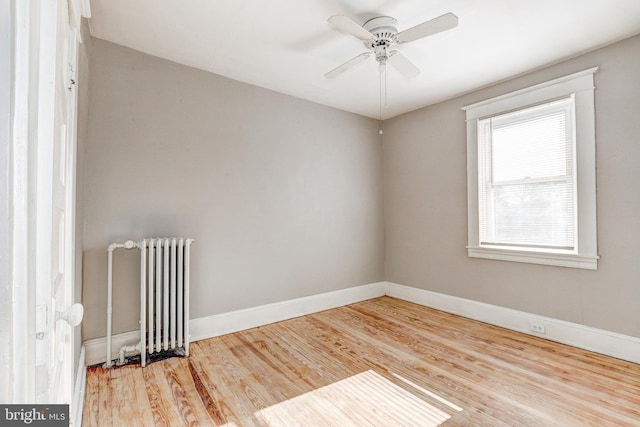 unfurnished room with wood-type flooring, radiator, and ceiling fan