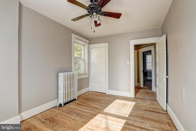 unfurnished bedroom featuring ceiling fan, light hardwood / wood-style floors, and radiator