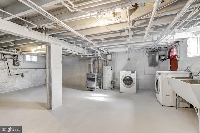 basement featuring sink, gas water heater, electric panel, and separate washer and dryer