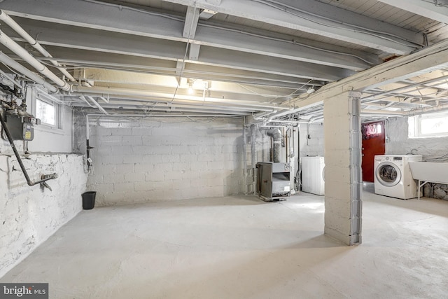 basement featuring sink, heating unit, and washer / clothes dryer