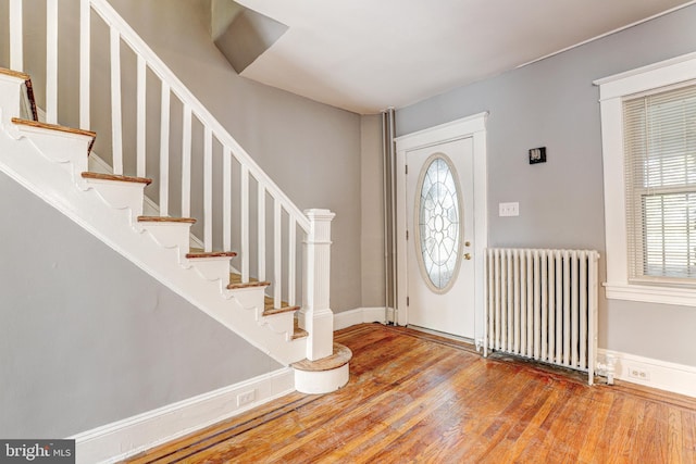 foyer entrance with radiator heating unit and wood-type flooring