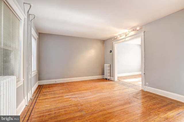 spare room featuring light wood-type flooring and radiator