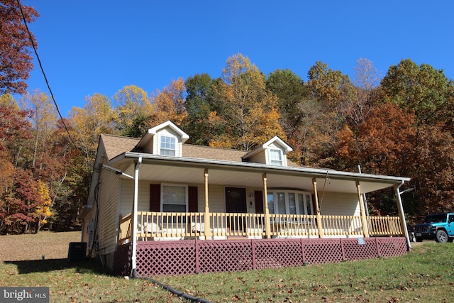 view of front facade with central AC, covered porch, and a front yard