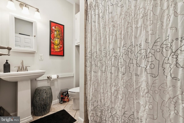 bathroom featuring toilet, curtained shower, and tile patterned flooring