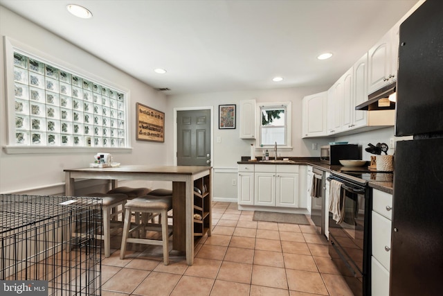 kitchen with sink, black appliances, white cabinets, and light tile patterned flooring