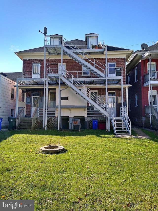 back of property featuring a fire pit and a lawn