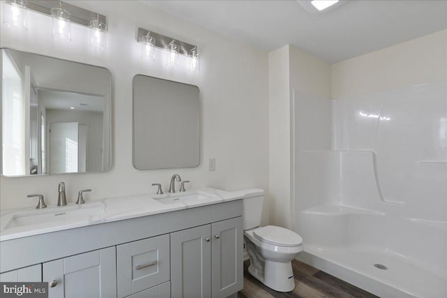 bathroom featuring hardwood / wood-style flooring, toilet, walk in shower, and vanity