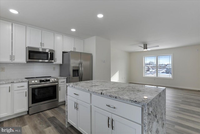 kitchen featuring a kitchen island, backsplash, white cabinets, and appliances with stainless steel finishes