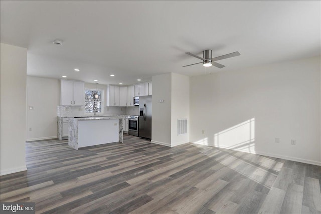 kitchen featuring hardwood / wood-style floors, white cabinets, a center island, stainless steel appliances, and backsplash