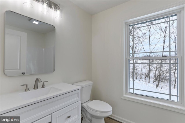 bathroom featuring a wealth of natural light, toilet, and vanity