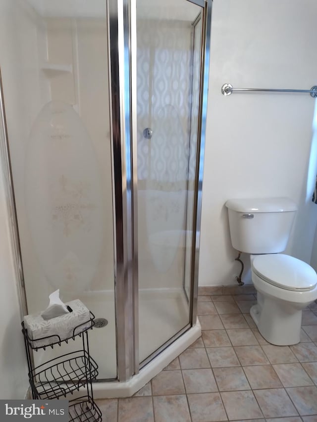 bathroom featuring tile patterned floors, a shower with shower door, and toilet