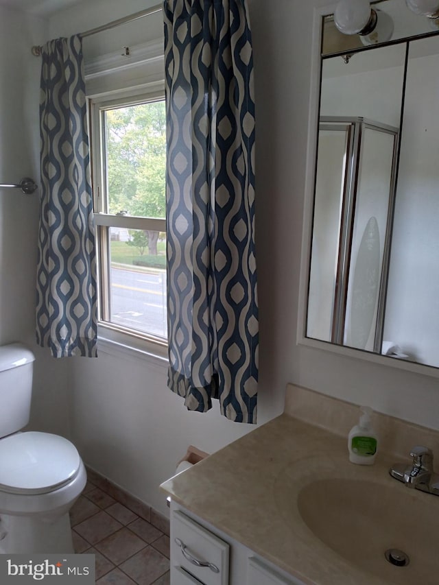 bathroom with toilet, a shower, vanity, and tile patterned floors