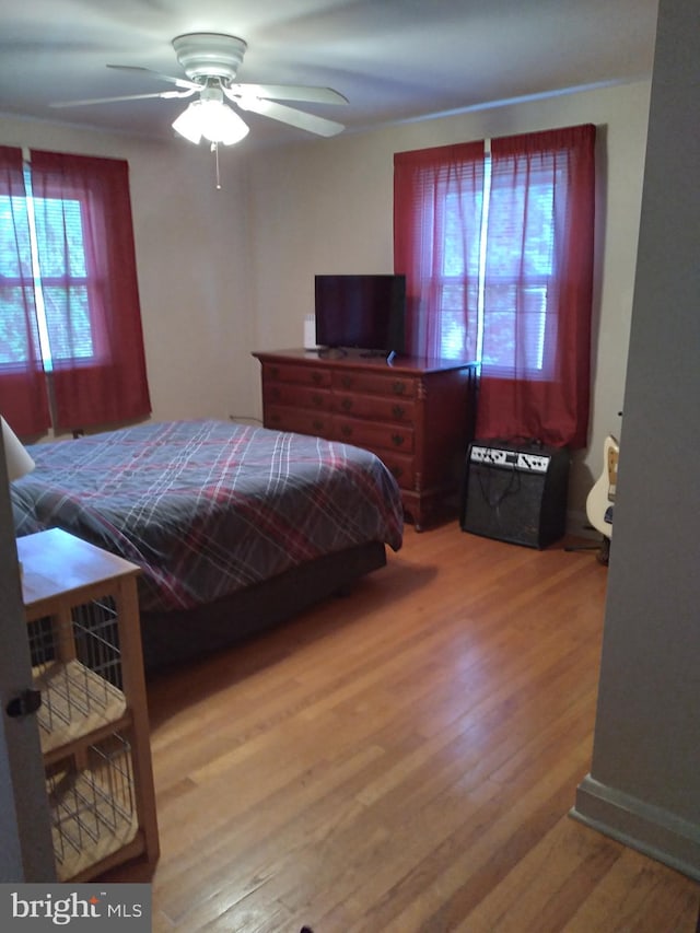 bedroom featuring multiple windows, wood-type flooring, and ceiling fan