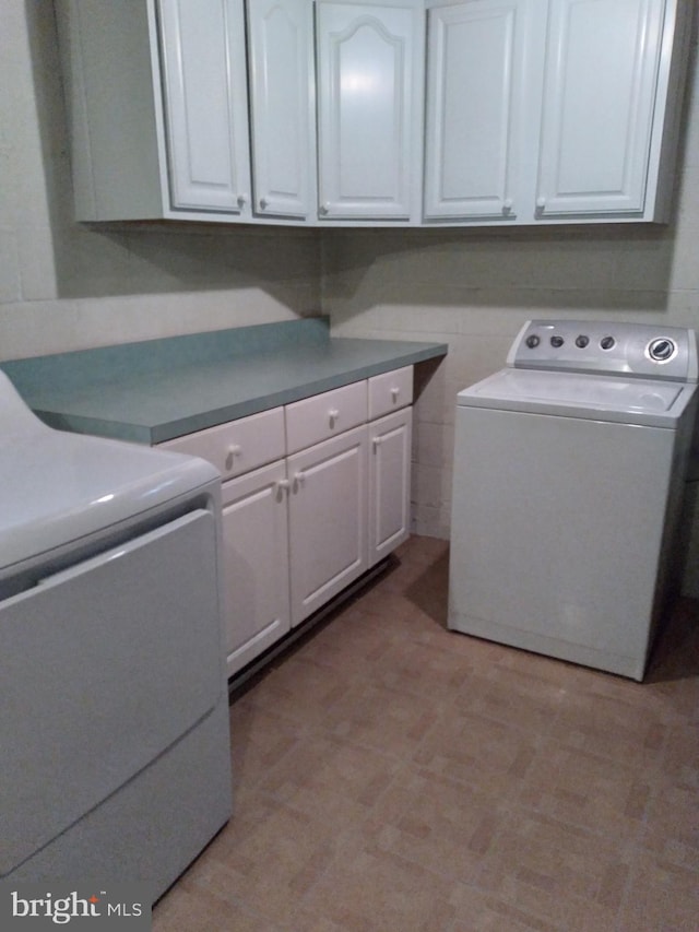 clothes washing area with washer / dryer and cabinets