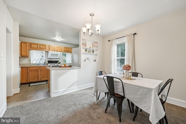 dining area featuring a notable chandelier, light carpet, and sink