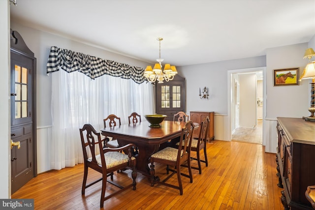 dining area with light hardwood / wood-style floors and a notable chandelier