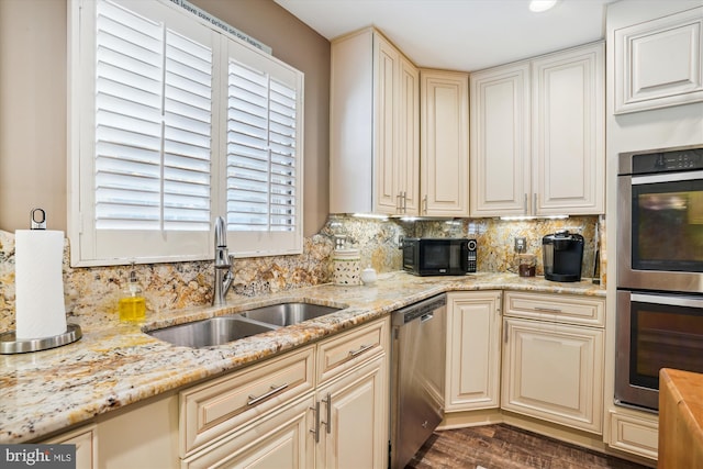 kitchen featuring tasteful backsplash, light stone counters, sink, and stainless steel appliances