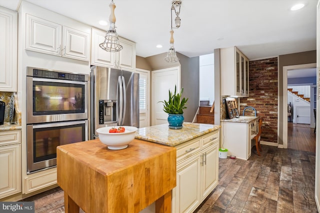 kitchen featuring light stone counters, a center island, stainless steel appliances, and dark hardwood / wood-style floors