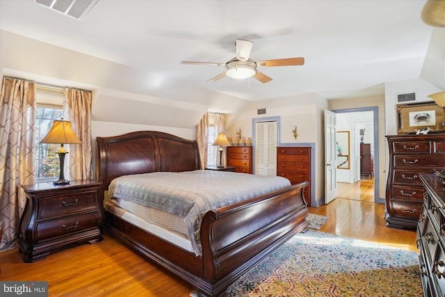 bedroom with vaulted ceiling, a closet, light hardwood / wood-style flooring, and ceiling fan