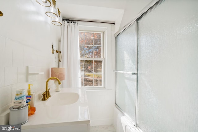 bathroom featuring sink, enclosed tub / shower combo, and tile walls