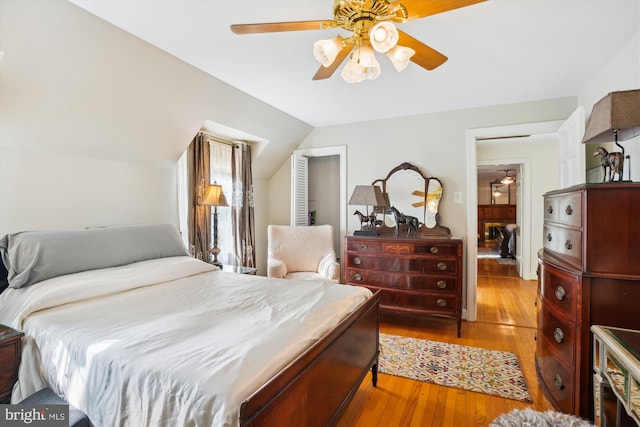 bedroom with ceiling fan, lofted ceiling, and light wood-type flooring