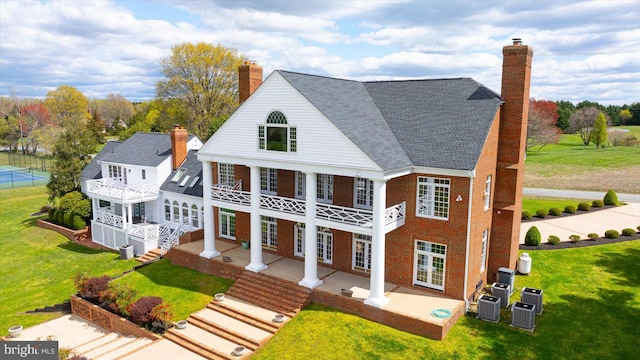 rear view of house featuring central AC, a lawn, and a balcony