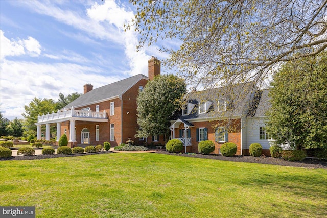 view of front of house with a balcony and a front yard