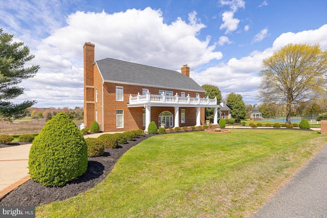 view of front of home featuring a front yard and a balcony