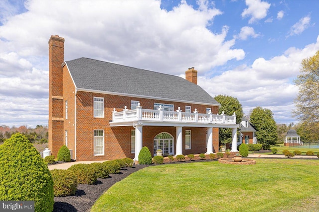 view of front facade featuring a balcony, a front lawn, and a fire pit