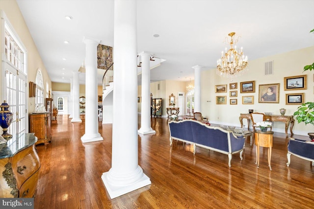 living room with an inviting chandelier, hardwood / wood-style floors, and ornate columns