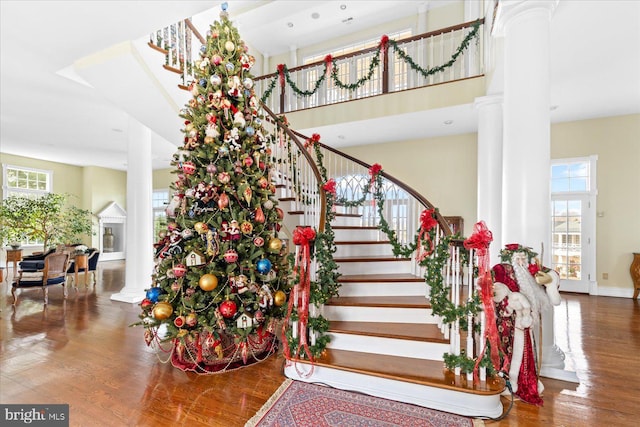 stairway with decorative columns, hardwood / wood-style flooring, and a high ceiling