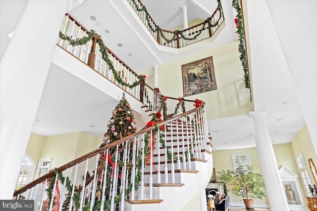 staircase with ornate columns and a high ceiling