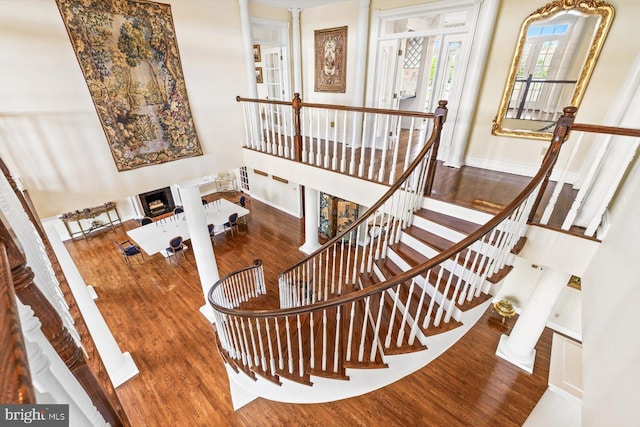 stairway with decorative columns and wood-type flooring