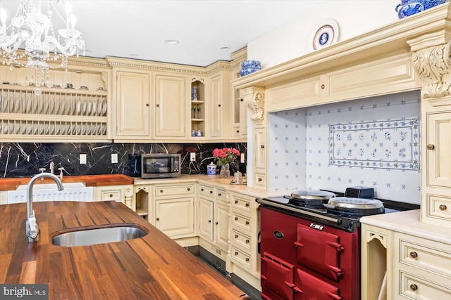 kitchen featuring cream cabinetry, hanging light fixtures, sink, a chandelier, and butcher block countertops