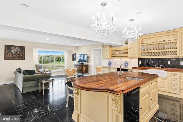 kitchen with a kitchen island with sink, wood counters, wine cooler, sink, and tasteful backsplash