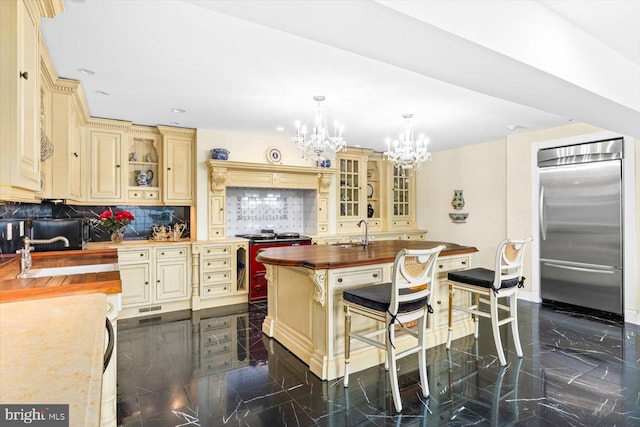 kitchen with stainless steel built in fridge, hanging light fixtures, wood counters, an inviting chandelier, and tasteful backsplash