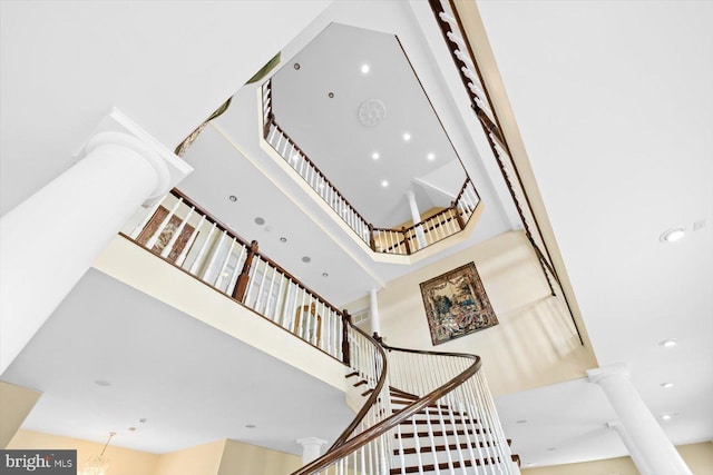 stairway with a high ceiling, ornate columns, and an inviting chandelier