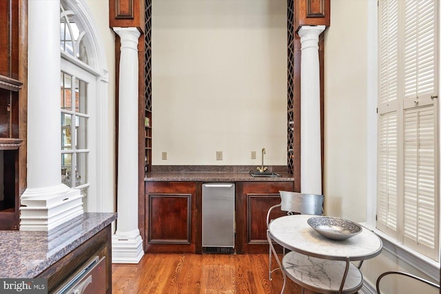 bar with sink, wood-type flooring, and decorative columns