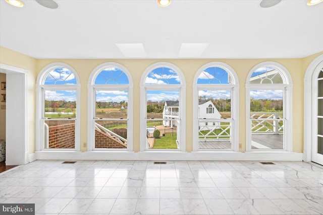 unfurnished sunroom featuring a skylight and plenty of natural light