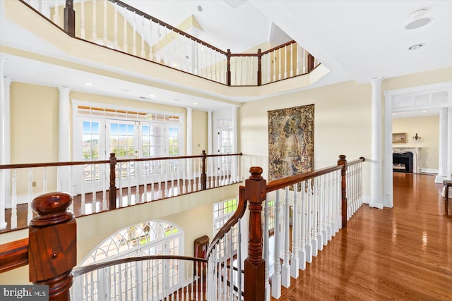 hallway featuring ornate columns, hardwood / wood-style flooring, and a towering ceiling