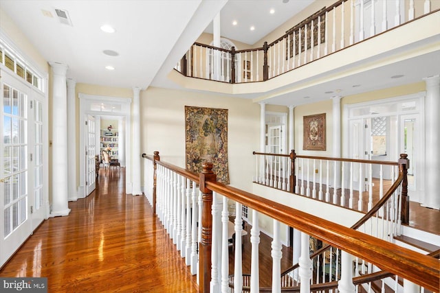 hallway with a towering ceiling, ornate columns, and dark hardwood / wood-style flooring