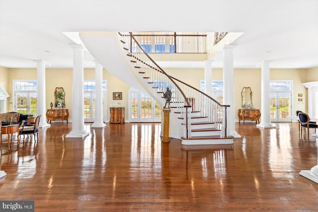 foyer entrance featuring a wealth of natural light, decorative columns, and dark hardwood / wood-style flooring