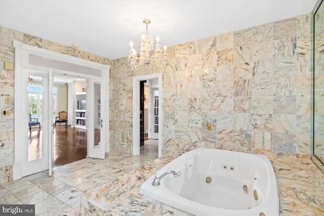 bathroom featuring a relaxing tiled tub and an inviting chandelier